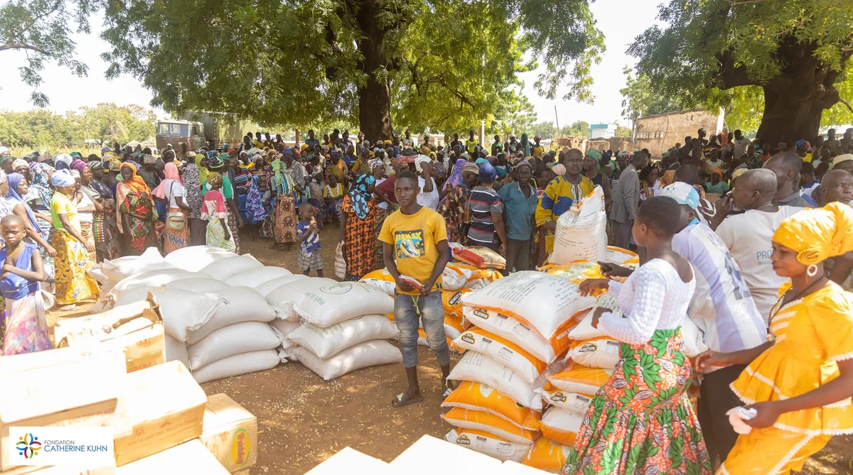 A community gathered around food supplies beneath the trees